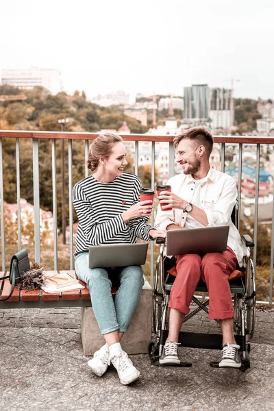 Freelancer sonriendo mientras bebe café con su colega discapacitado — Foto de Stock