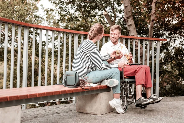 Ανάπηρο άνθρωπο που χαμογελώντας σε νεαρή γυναίκα ενώ κάθεται στο πάρκο μαζί της — Φωτογραφία Αρχείου