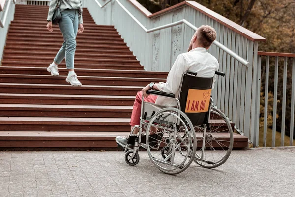 Инвалид сидит в инвалидном кресле и смотрит на лестницу — стоковое фото