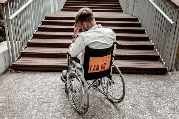 Hombre discapacitado frente a una gran barrera y sin esperanza — Foto de Stock