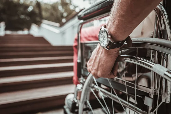 Närbild av mans hand som håller ratten i rullstolen — Stockfoto