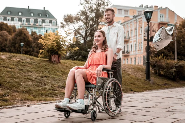 Chica discapacitada sintiéndose segura mientras su novio empuja su silla de ruedas — Foto de Stock