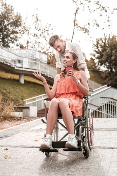 Chica feliz sentada en la silla de ruedas y hablando con su novio — Foto de Stock