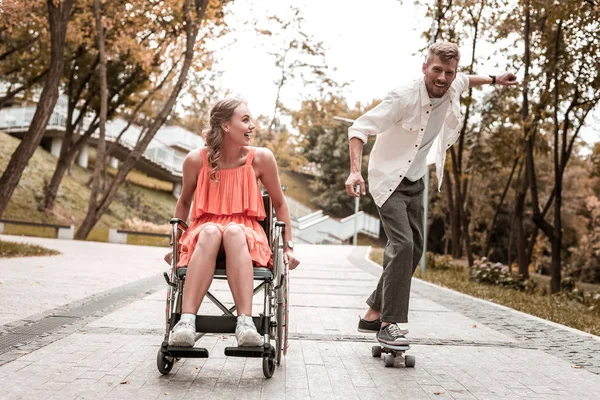 Chica discapacitada buscando impresionado mientras su novio montar penny board — Foto de Stock