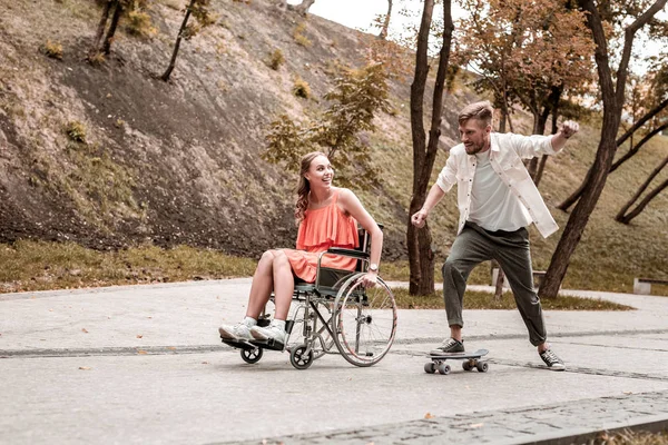 Chica discapacitada mirando a su novio montando tablero de peniques y sonriendo — Foto de Stock