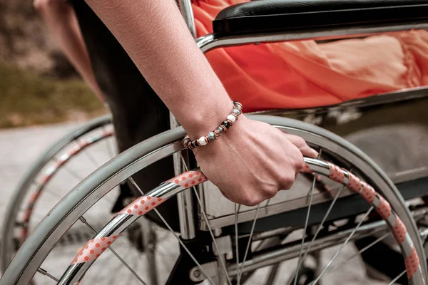 Persona con discapacidad sentada en la silla de ruedas y poniendo la mano en el volante —  Fotos de Stock