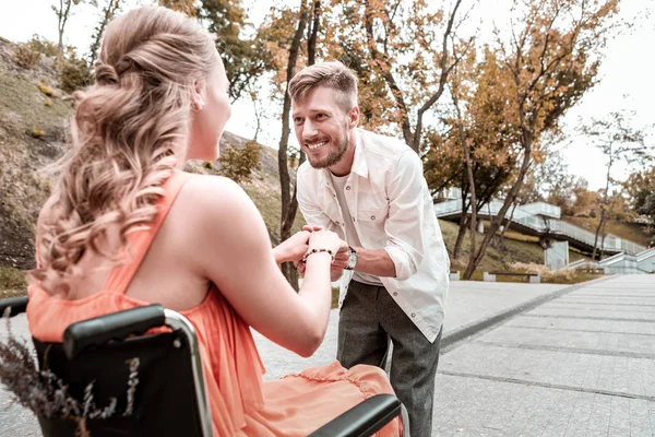 Liebender Mann lächelt und berührt Hände seiner behinderten Freundin — Stockfoto