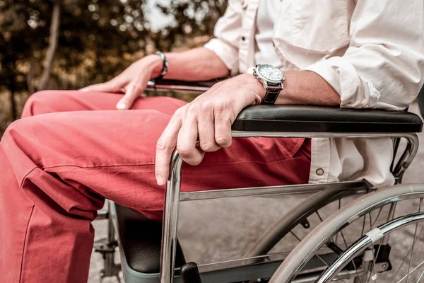 Primer plano del joven sentado en la silla de ruedas con las manos relajadas — Foto de Stock