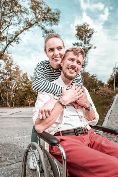Positieve vrouw toont haar steun tijdens het knuffelen van haar handicap vriendje — Stockfoto