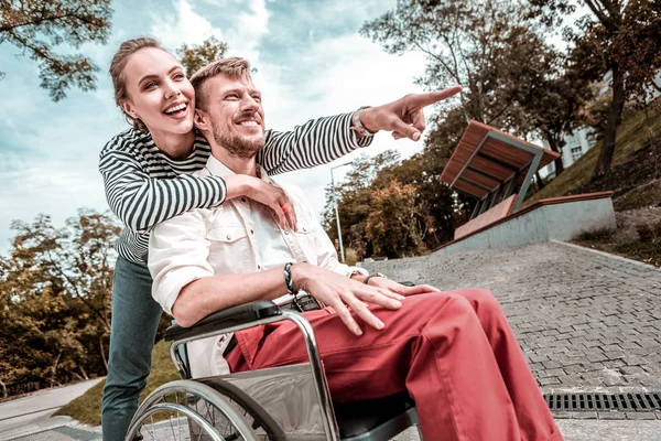 Emotionele vrouw die lacht terwijl het maken van de excursie voor gehandicapte vriend — Stockfoto