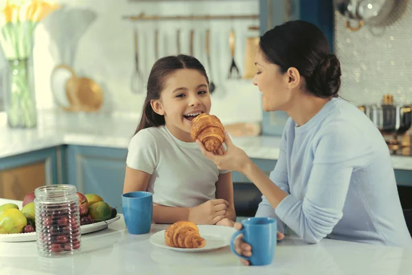 Bonita madre sonriente dando croissant a su hijo —  Fotos de Stock