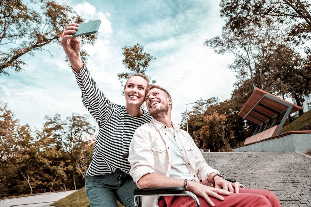 Disabled man smiling while taking selfie with beloved woman