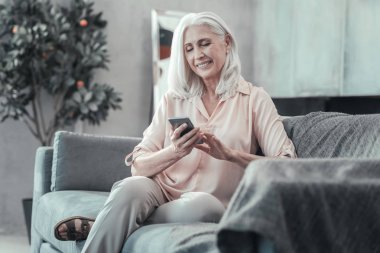 Onun smartphone kullanarak memnun yaşlı kadın