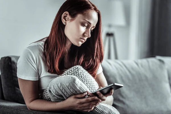 Negative delighted female person looking at her gadget