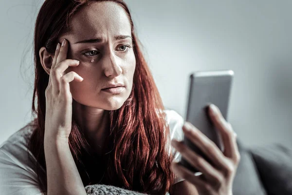 Persona femenina infeliz mirando su dispositivo — Foto de Stock