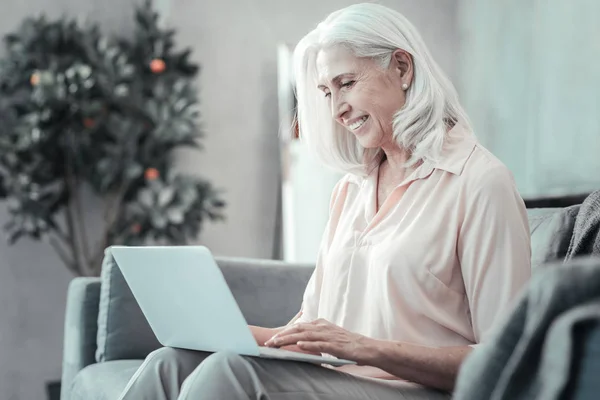 Joyful aged woman surfing the Internet