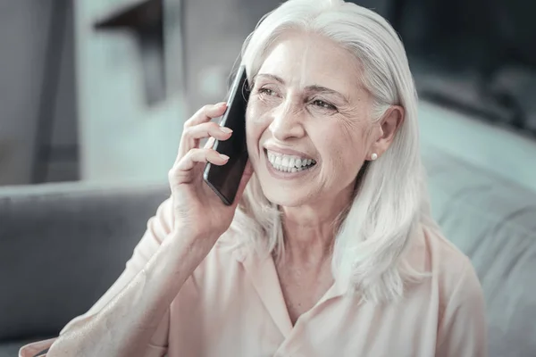 Cheerful aged woman holding her smartphone