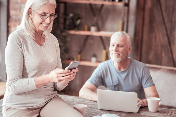 Portrait of joyful elderly woman using mobile phone