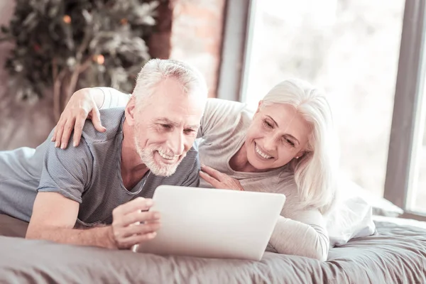 Famiglia allegra sdraiata sul letto con un computer portatile — Foto Stock