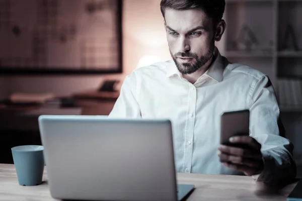 Geconcentreerde brunette werken met zijn gadgets — Stockfoto