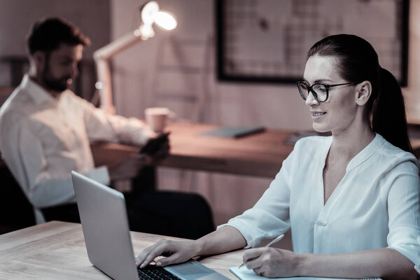 Сконцентрированная молодая женщина сидит на своем рабочем месте
