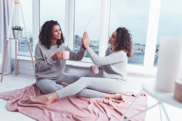 Two friends enjoying coffee break sitting near window