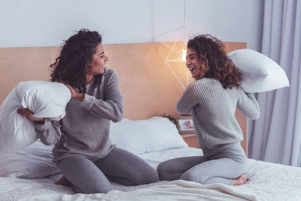 Dos amigos riendo disfrutando de la batalla de almohadas en casa — Foto de Stock