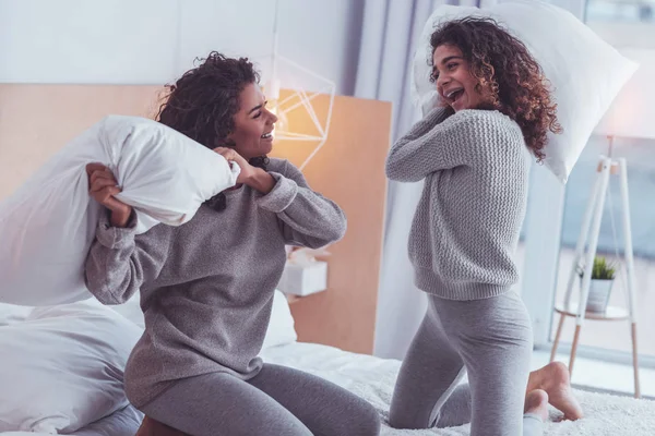 Felices hermanos sintiéndose alegres mientras tienen batalla de almohadas — Foto de Stock