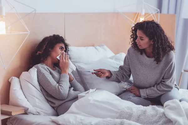 Caring sister taking care of her sick sibling