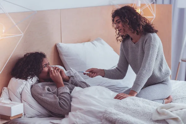 Caring girl bringing thermometer to her sick cousin — Stock Photo, Image