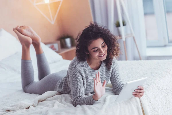 Kudrnatá dívka s úsměvem, s video chat s přítelem — Stock fotografie