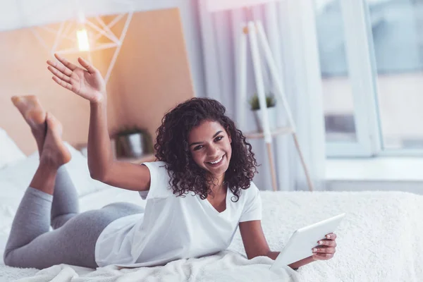 Chica bonita rizada sonriendo saludando a sus invitados — Foto de Stock