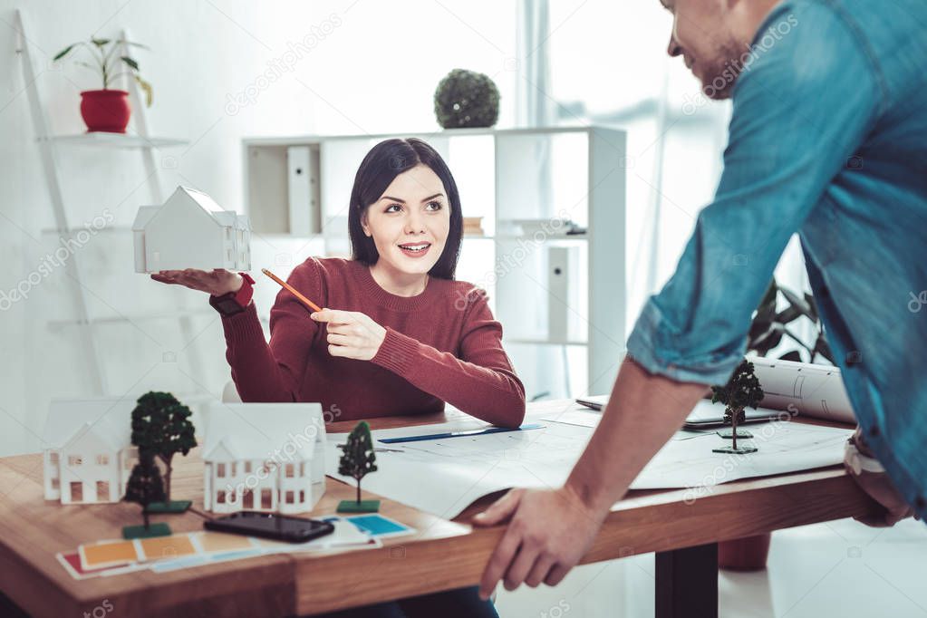 Pleased architect demonstrating model of house