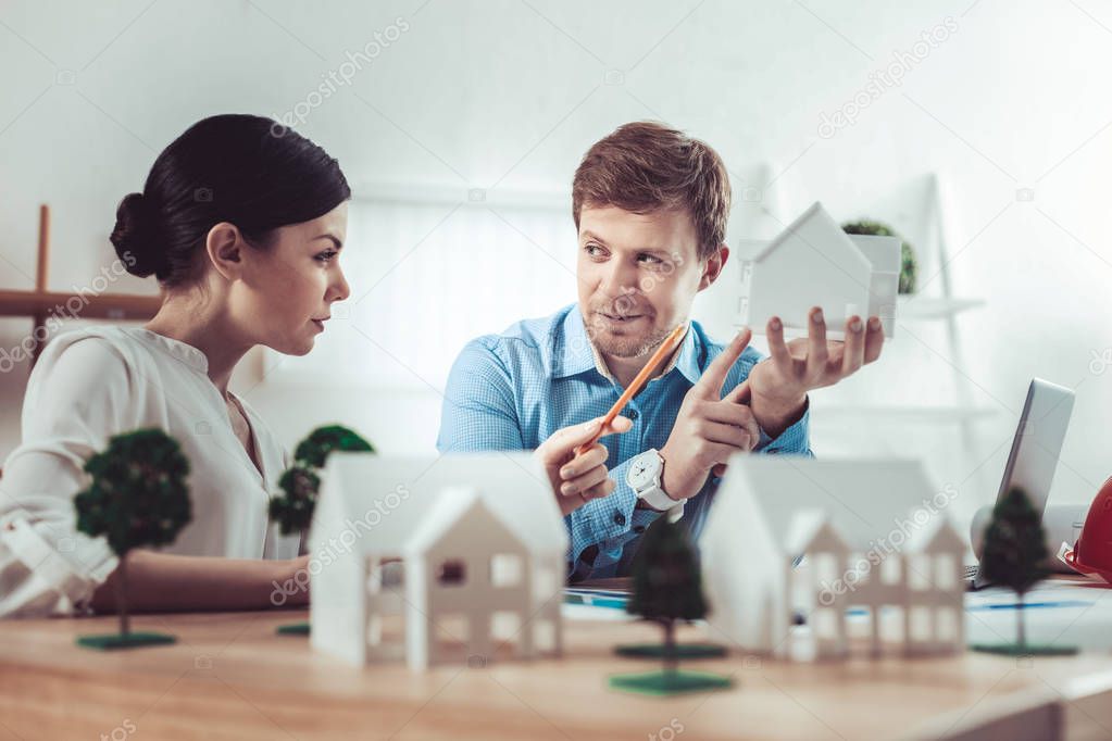 Delighted young woman pointing at little house