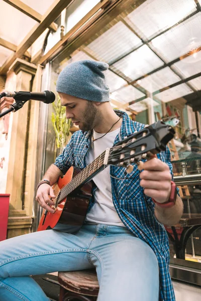 Ernsthafter männlicher Gitarrist reguliert den Sound in der Gitarre — Stockfoto