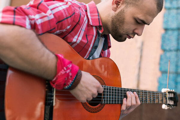 Thoughtful street musician involving in guitar practice