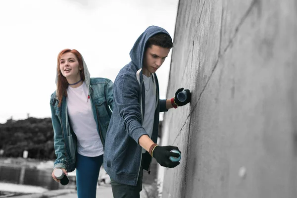 Två tonåringar bär jackor med hoodies teckning graffiti i staden — Stockfoto