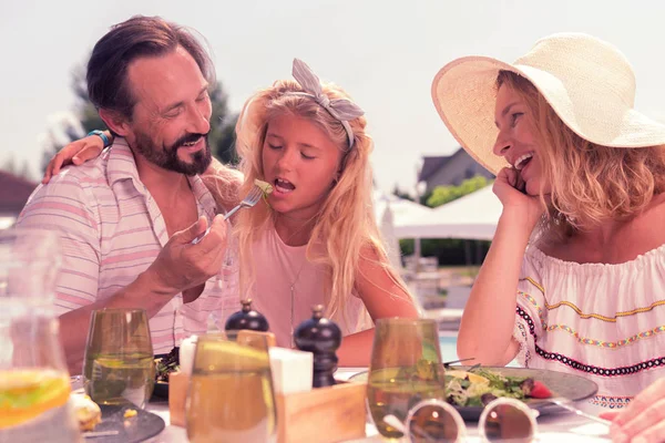 Bello padre premuroso che nutre sua figlia con insalata — Foto Stock