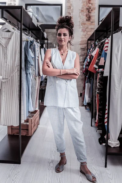 Владелец модного бутика стоит между стендами с одеждой — стоковое фото