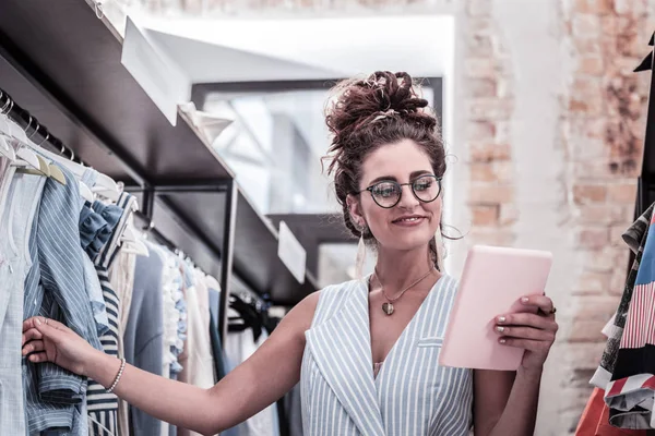 Boutique trabajador sosteniendo la tableta mientras comprueba los tamaños disponibles de vestidos de verano — Foto de Stock