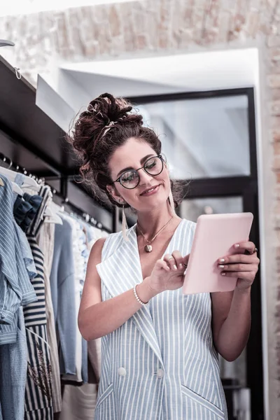 Geïnspireerd stralende ontwerper roze tablet te houden tijdens het werken aan nieuwe uitrustingen — Stockfoto