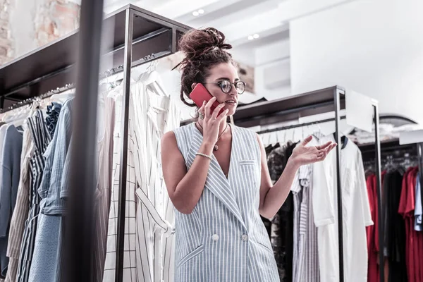 Dark-haired ontwerper dragen gestreept blauw vest spreken door de telefoon — Stockfoto