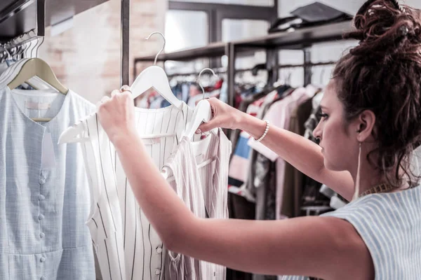 Nuttige assistent van fashion boutique zetten nieuwe zomer jurken op hangers — Stockfoto