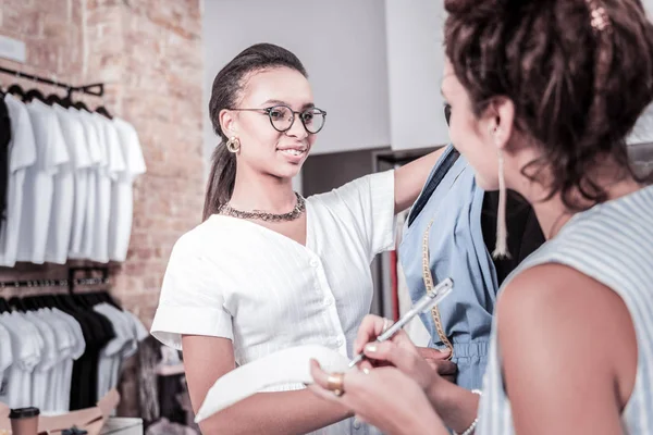 Diseñador sonriente usando vestido blanco sintiéndose alegre trabajando con su pareja — Foto de Stock