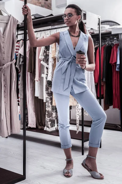 Owner of fashion boutique wearing trousers and vest having coffee break