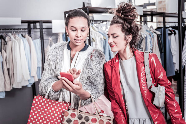 Dark-haired stylish businesswoman showing her photos her best friend