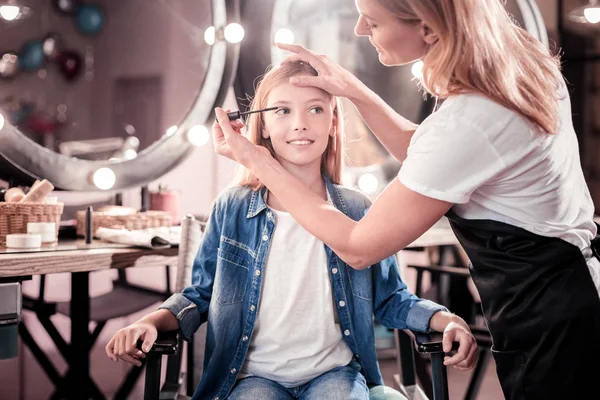 Концентрированная девушка делает макияж в салоне — стоковое фото