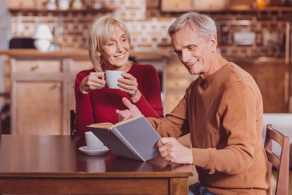 Pensionista sonriente leyendo un libro — Foto de Stock