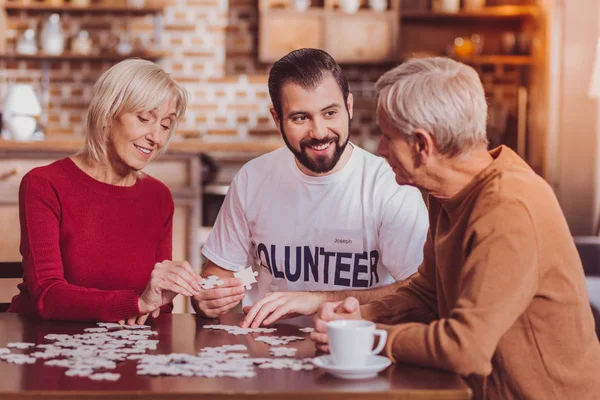 Voluntario inspirado jugando un juego con los pensionistas — Foto de Stock