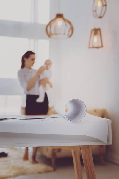 Mãe trabalhadora alimentando seu bebê de pé perto da mesa de trabalho — Fotografia de Stock